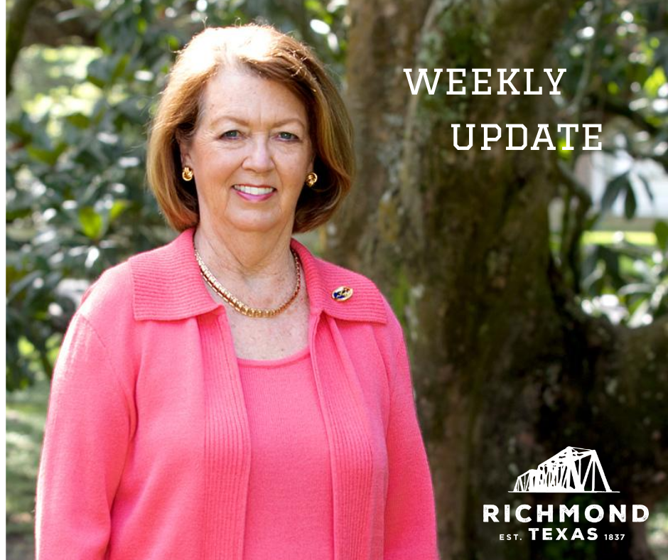 Mayor Moore in Pink sweater front of tree- Weekly update